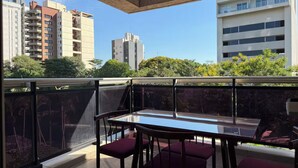 A balcony with a glass table and chairs, overlooking a cityscape with buildings and greenery. - LUXURY APARTMENT IN ASUNCIÓN, PARAGUAY: THE TOWER (Asunción)
