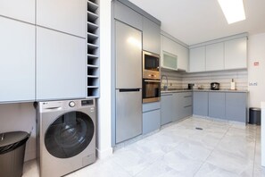 A modern kitchen with built-in appliances, grey cabinetry, and a stainless steel washing machine. - Roots of Gaia by Hommelier (Vila Nova de Gaia)