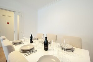 Une table à manger dressée avec des assiettes, des verres et des bouteilles de vin, entourée de chaises.