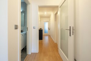 Un couloir doté d’un plancher en bois, de murs blancs et d’une porte donnant sur une salle de bain.