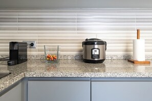 A kitchen with a granite countertop, a rice cooker, a glass container with metal objects, and a paper towel holder. - Roots of Gaia by Hommelier (Vila Nova de Gaia)