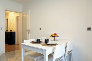 A dining area with a white table, two chairs, a fruit bowl, and a small side table with a lamp. - Roots of Gaia by Hommelier (Vila Nova de Gaia)