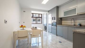 Une cuisine moderne avec des meubles gris, un four en acier inoxydable et un micro-ondes encastré.