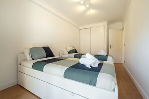 A bedroom with two beds, a wardrobe, and a door leading to another room. - Roots of Gaia by Hommelier (Vila Nova de Gaia)