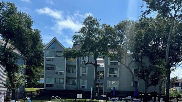 Een zwembad met helder water, omringd door ligbedden en een gebouw op de achtergrond.