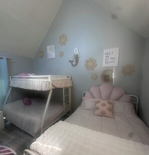 Ein Schlafzimmer mit Etagenbetten, einer Wand mit dekorativen Blumen und einem Schild mit der Aufschrift 'MEET ME AT THE BEACH'.