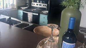 Een keuken met blauwgroene kastjes, een zwarte koelkast, een magnetron en een spoelbak.