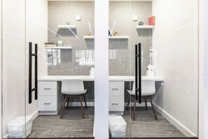 Ein modernes Badezimmer mit einem weißen Waschtisch, zwei weißen Stühlen, einer Glasdusche und einer Arbeitsplatte aus Granit.
