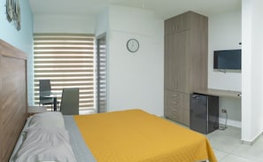 A bedroom with a bed, a desk, a chair, a wardrobe, and a clock on the wall. - Departamento Marina · Alberca · Balcón · Cerritos (Mazatlán)