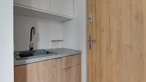 Een keuken met een gootsteen, kastjes en een houten deur.
