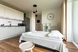 Un dormitorio moderno con cama, mesita de noche y vistas a una zona de cocina.