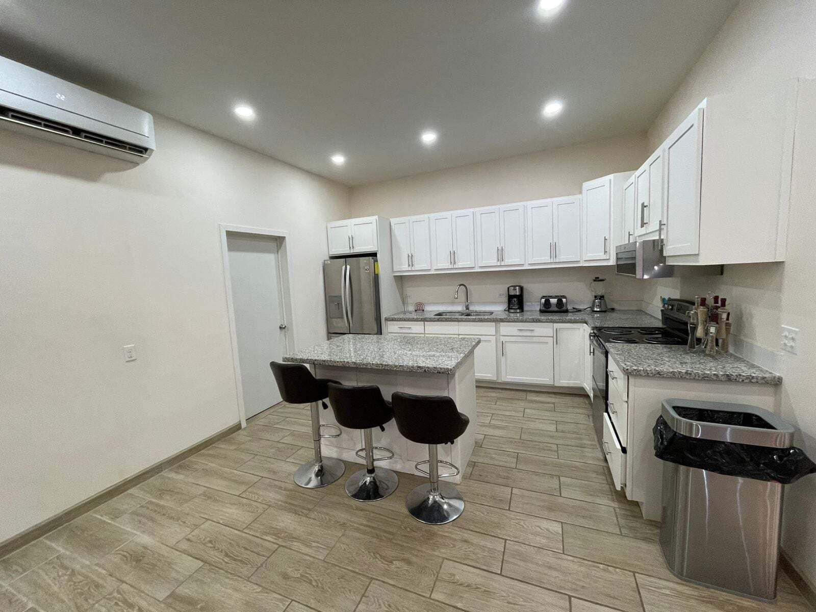 A wide-angle interior perspective capturing the kitchen from a rear viewpoint inside La Kasa #1, showcasing the full counter layout, cabinetry, and modern appliances.
