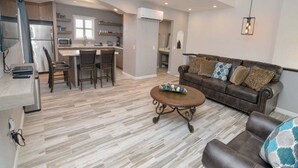 A modern living room with a brown leather sofa, a coffee table, and a dining area with a kitchen in the background. - Hacienda Resort San Felipe - Spacious Dual Unit Vacation Rental 1819 (San Felipe)