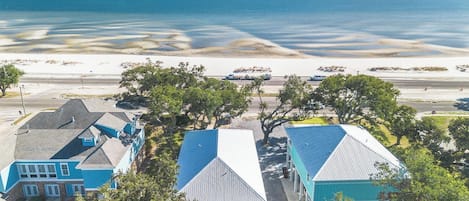 Una propiedad costera con varias construcciones, vista despejada del océano y una playa arenosa.