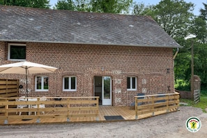 A brick building with a wooden deck, a door, and a window.