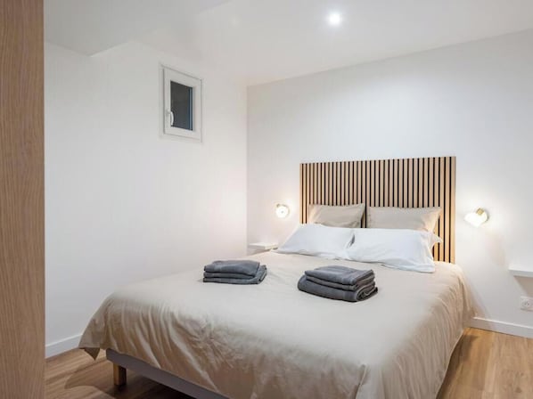 A bedroom with a bed, bedside lamps, and a headboard.