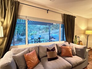 A living room with a large window, a sofa with cushions, a table, and chairs outside. - Three Rivers Hideaway Near Sequoia National Park with Mountain View’s (Three Rivers)