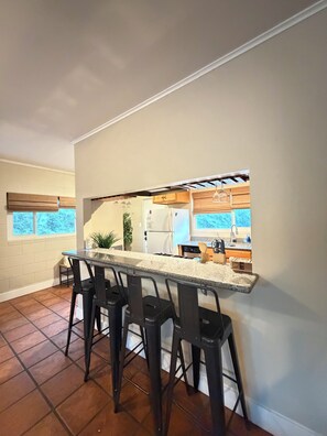 A kitchen with a bar area, black bar stools, a refrigerator, and a window with blinds. - Three Rivers Hideaway Near Sequoia National Park with Mountain View’s (Three Rivers)
