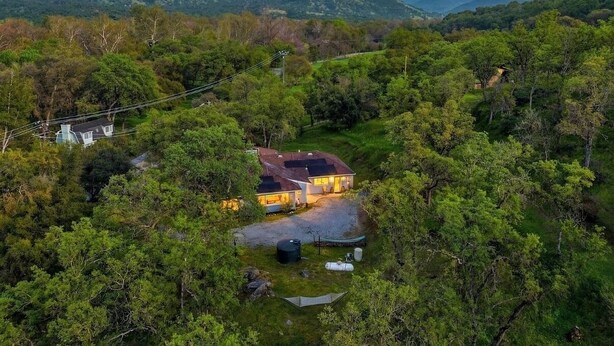 Una casa rodeada de un bosque frondoso con una montaña al fondo.