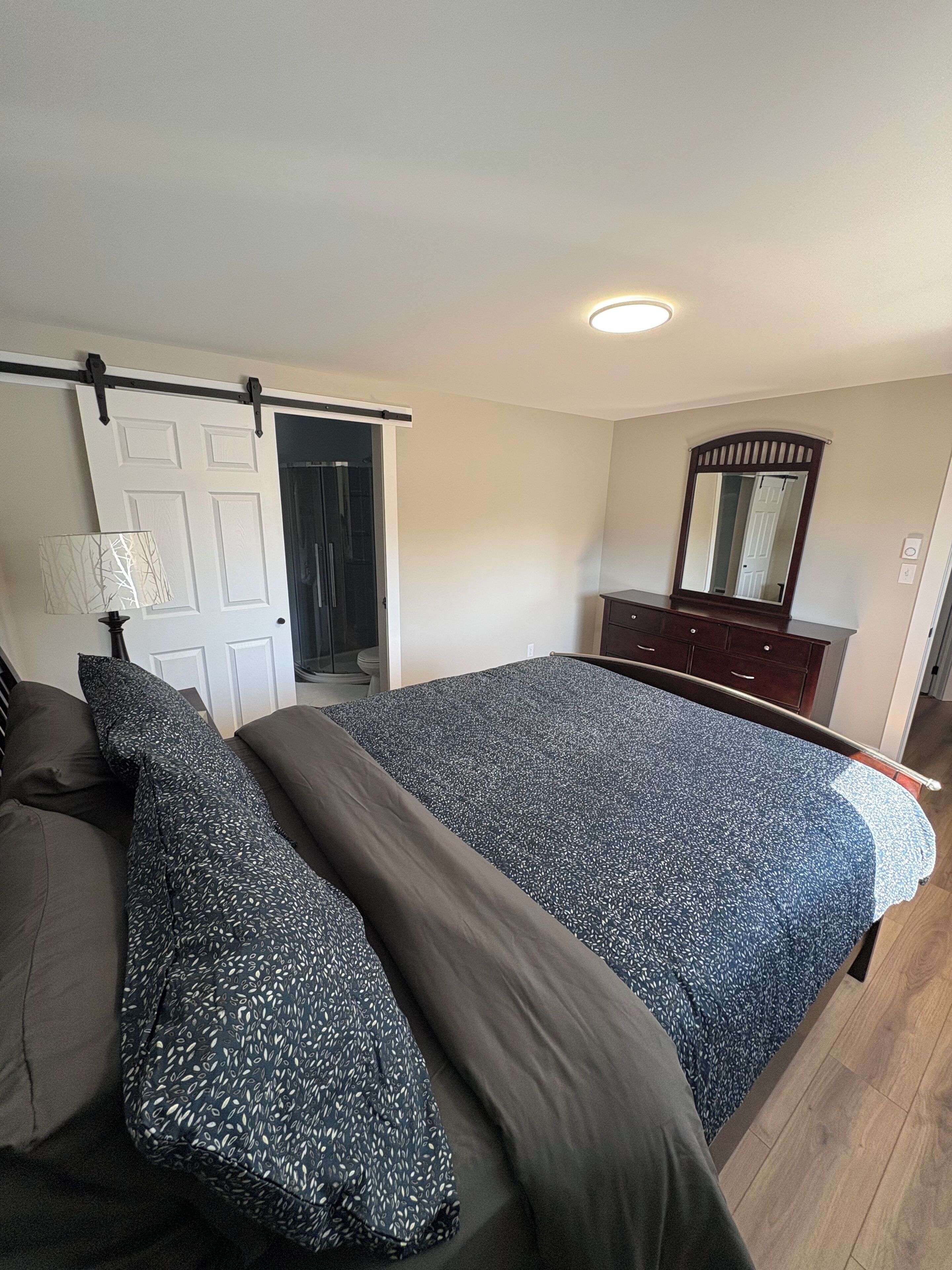 Une chambre à coucher avec un lit, une commode, un miroir et une porte coulissante.