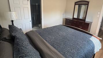 Une chambre à coucher avec un lit, une commode, un miroir et une porte coulissante.