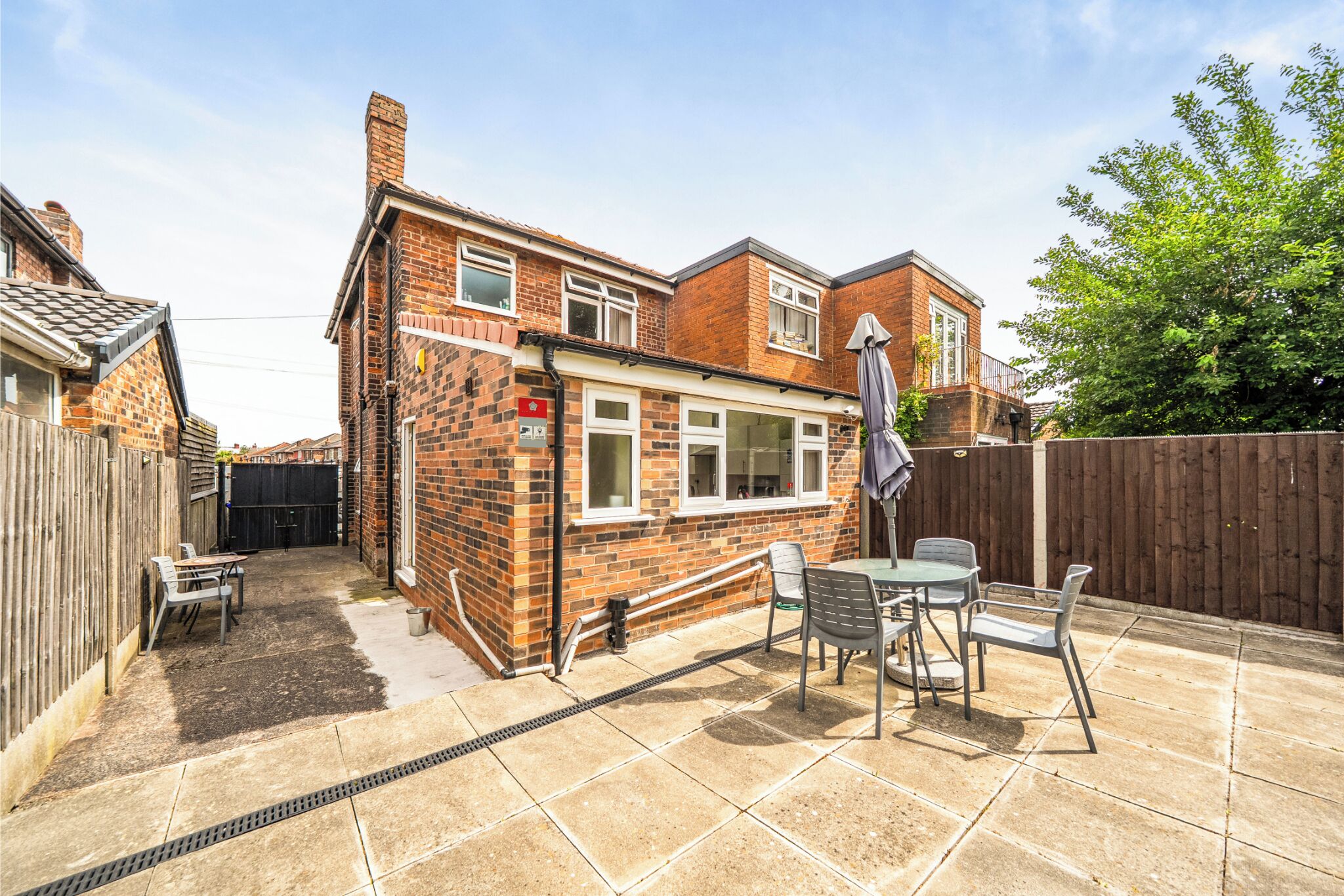 A brick house with a patio, a table, and chairs.