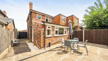 A brick house with a patio, a table, and chairs.