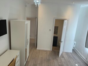 Ein Zimmer mit einem weißen Kleiderschrank, einer Tür zu einem Badezimmer und einem Holzboden.