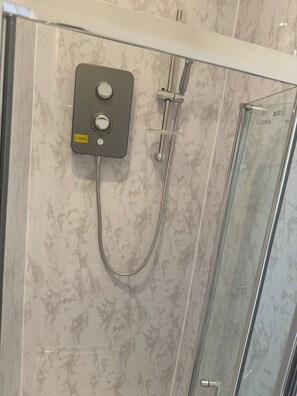 Eine Dusche mit Bedienfeld, Glastür und Wänden mit Marmoroptik.