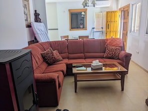 A living room with a sectional sofa, a coffee table, a small table with a remote control, and a wall-mounted mirror. - Beautiful House, Sleeps 7 with Private Pool (Iznajar)