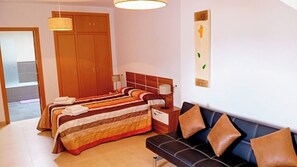Ein Hotelzimmer mit zwei Betten, einem Sofa, einem Holzschrank und einem an der Wand hängenden Kunstwerk.