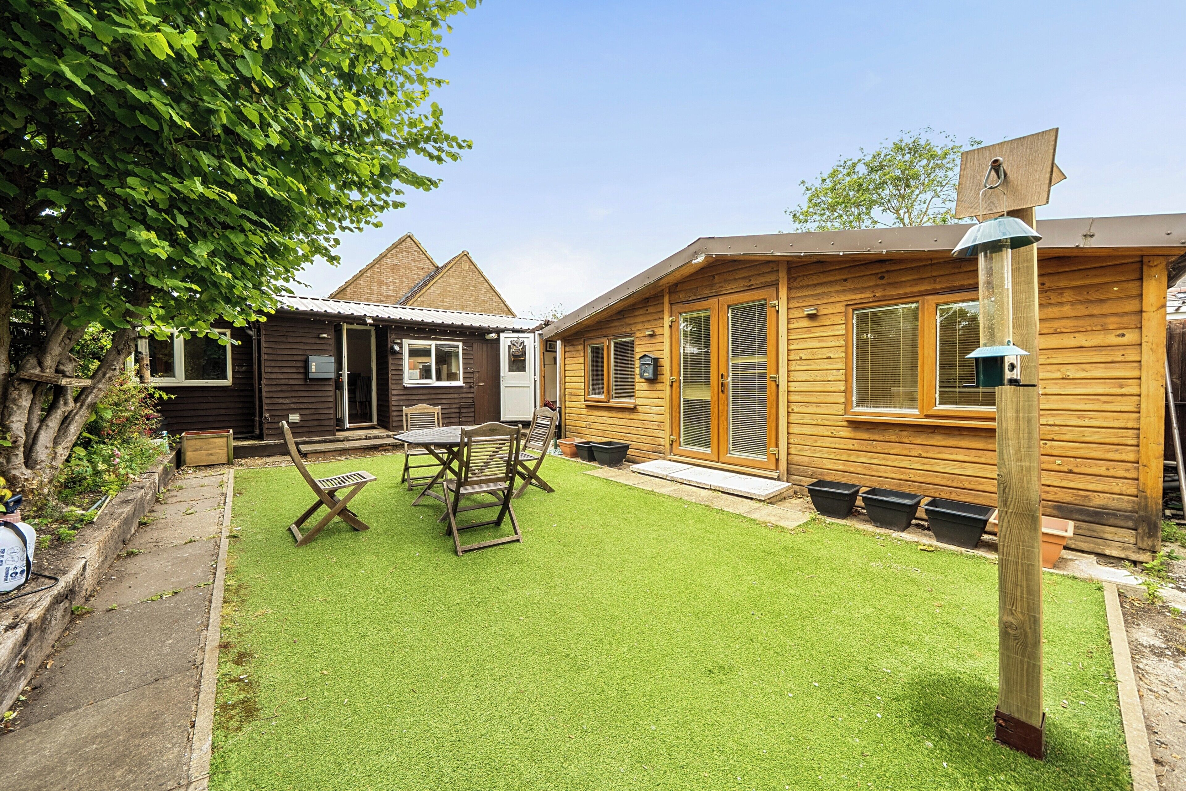 A wooden cabin with a patio, a table, and chairs.