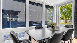 Un comedor moderno con una mesa grande y sillas, ventanas amplias y vistas al exterior.