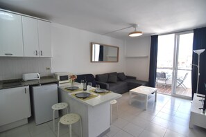 A compact living space with a kitchenette, a dining area, a sofa, and a balcony with a view. - SYMAR BAJO - VISTAS AL CANAL (Roses)