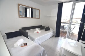 A hotel room with two beds, a desk, a chair, a window with curtains, and a balcony. - SYMAR BAJO - VISTAS AL CANAL (Roses)