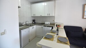 A compact kitchen with white cabinets, a dishwasher, a coffee maker, and a toaster. - SYMAR BAJO - VISTAS AL CANAL (Roses)