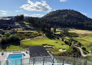 A resort with a swimming pool, a golf course, and a mountainous backdrop.