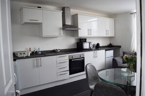 Una cocina moderna con armarios blancos, un horno negro y una mesa de comedor de vidrio.
