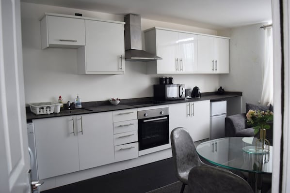 Una cocina moderna con armarios blancos, un horno negro y una mesa de comedor de vidrio.
