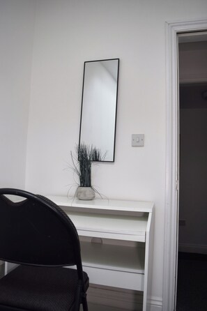 A white desk with a mirror, a potted plant, and a black chair in a room with a white door. - Modern 2Bed Apartment Sleeps 6 (Ilkeston)