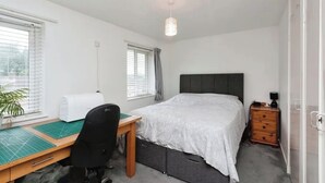 A bedroom with a bed, desk, chair, and a small dresser. - Spacious 4-Bedroom Family Home Sleeps 8 (Bordon)