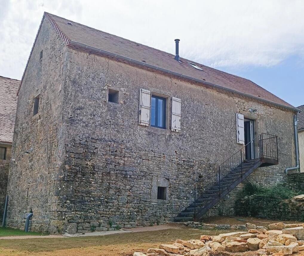 Un bâtiment en pierre avec un escalier menant à un balcon.