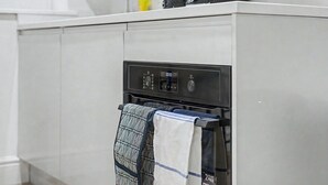 A kitchen with a built-in oven, a digital control panel, and a towel rack with patterned towels. - GuestReady - Modern 1bed in Liverpool (Liverpool)