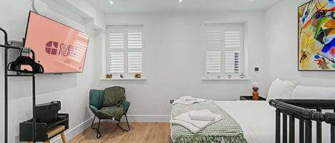 Une chambre à coucher avec un lit, une chaise, un téléviseur et un berceau.