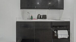 Una cocina pequeña equipada con un lavamanos, un hervidor y un horno.