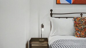 Un dormitorio con una cama, una mesita de noche, una lámpara y un cuadro en la pared.