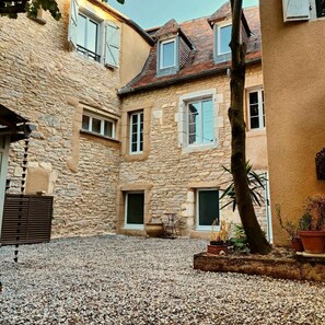 Ein Innenhof mit Steingebäuden, Kiesboden und Topfpflanzen.