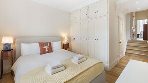 Habitación de hotel con cama, mesitas de noche, un amplio armario y una escalera.
