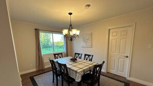 Un comedor con una mesa, sillas, una araña, una ventana y una puerta.
