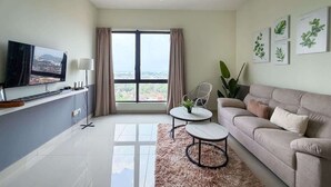 Ein modernes Wohnzimmer mit einer Couch, zwei Couchtischen, einem Fernseher und einem großen Fenster mit Vorhängen.